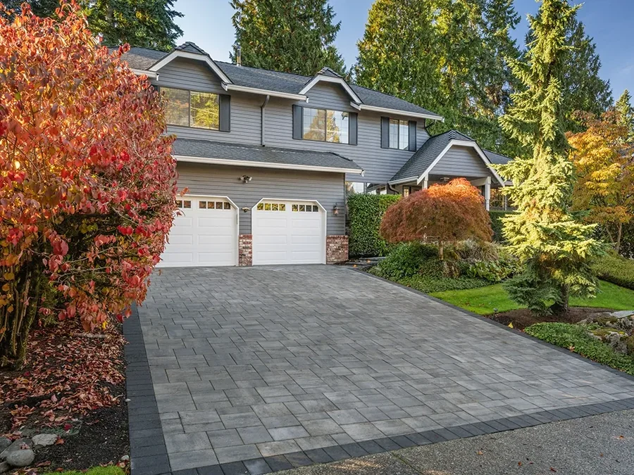Paver driveway leading to a double garage with autumn planting alongside.